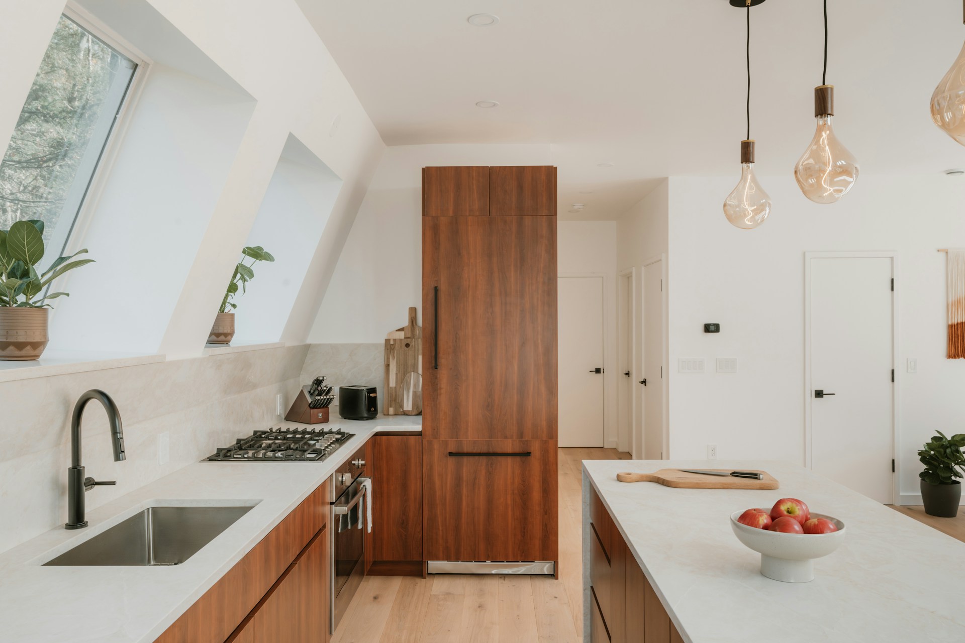 A bright, newly remodeled kitchen with walnut cabinets, stone countertops and pendant lighting